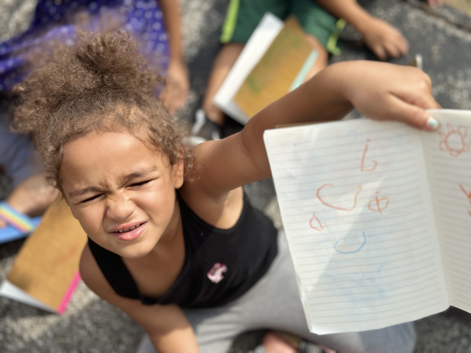 A child holding up her notebook to share her work